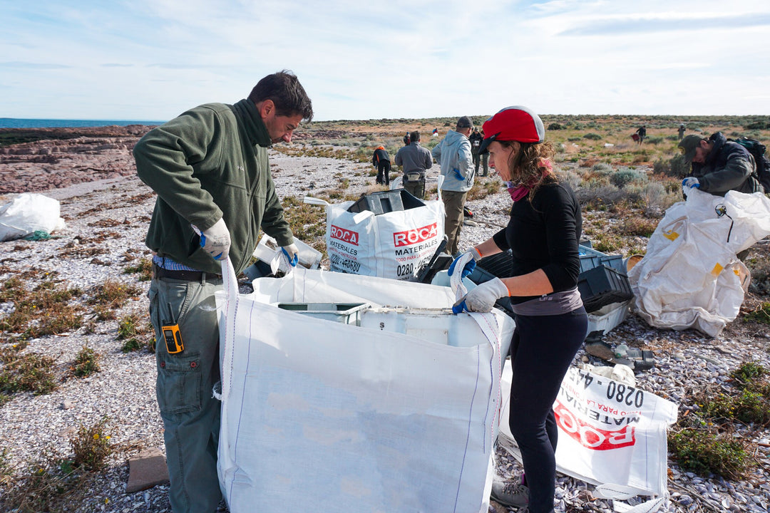 Several people are bagging trash on the beach as part of a program to remove plastic waste (PP, HDPE, Nylon, and others) from the fishing industry in remote areas like Patagonia, Argentina